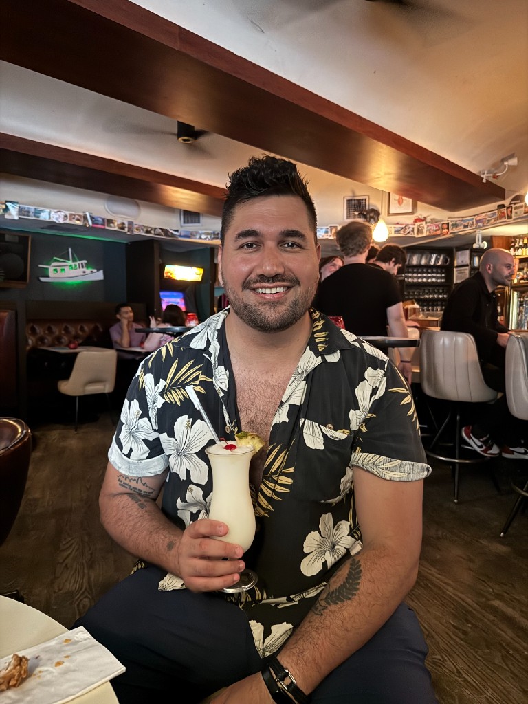 Darren holding a tropical drink at a bar